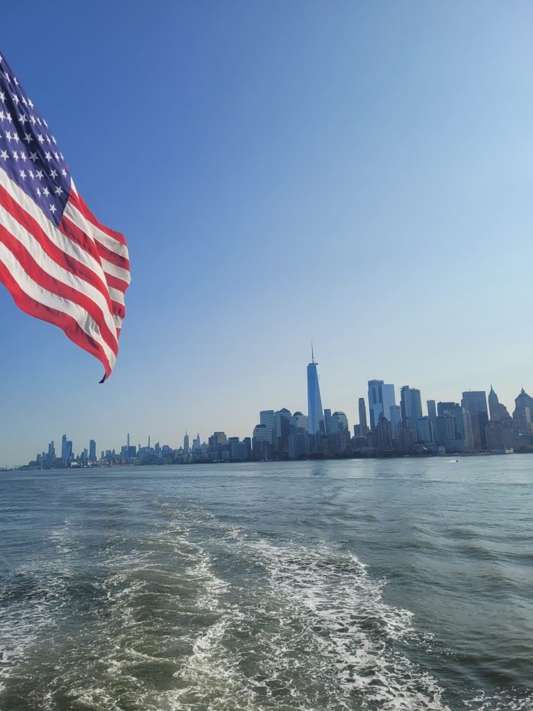 View of Manhattan from ferry with flag in foreground. 